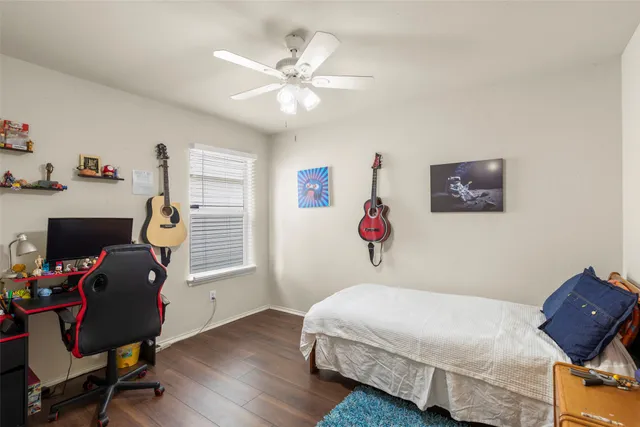 a bedroom with a bed a computer on a desk and chair