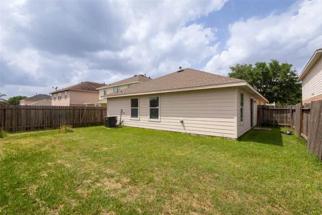 a yellow house sitting in middle of the grass near a yard