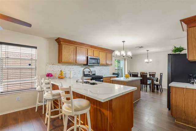 a kitchen with a dining table chairs and wooden floor