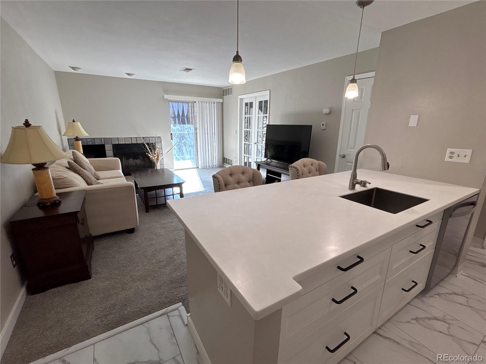 2575 South Syracuse Way, Unit J102 Denver, CO 80231 - Photo 3 of 13 a large bedroom with bed and a flat tv screen on dresser