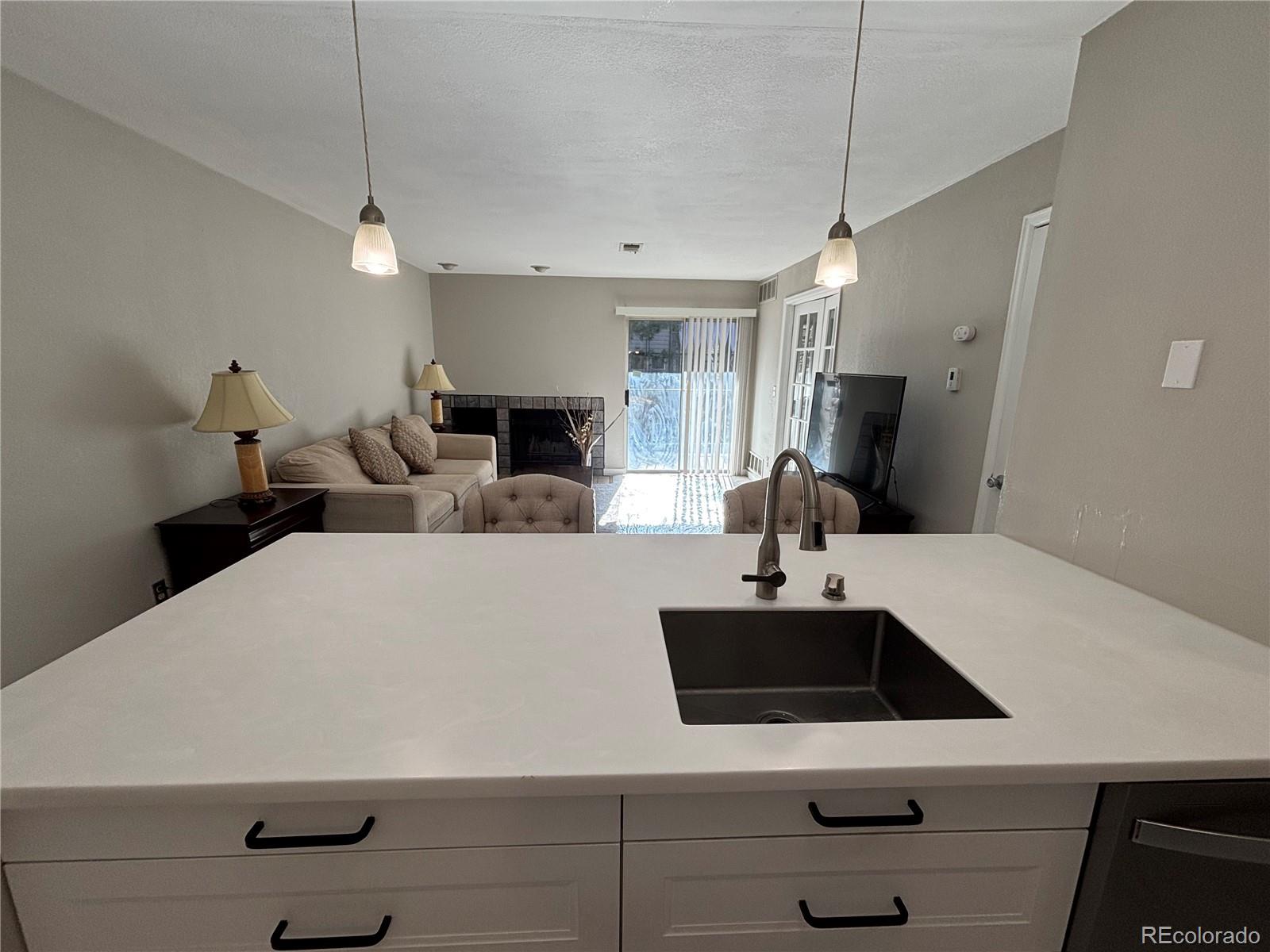 2575 South Syracuse Way, Unit J102 Denver, CO 80231 - Photo 6 of 13 a large white kitchen with stainless steel appliances a sink dishwasher a microwave a refrigerator and white cabinets