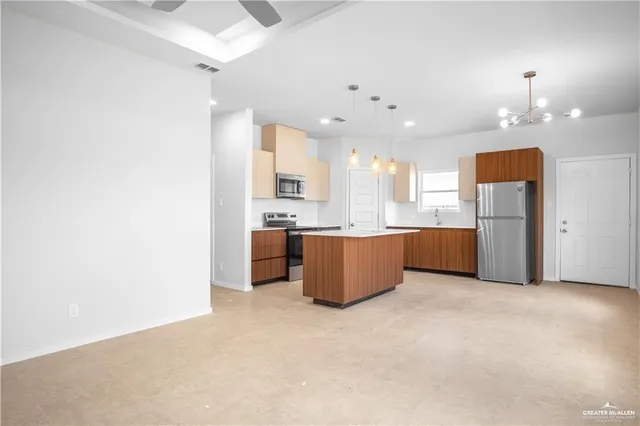 a large kitchen with stainless steel appliances kitchen island a large counter top and a refrigerator