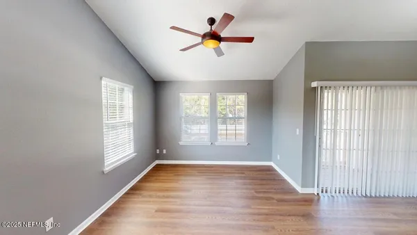 a view of an empty room with wooden floor and a window