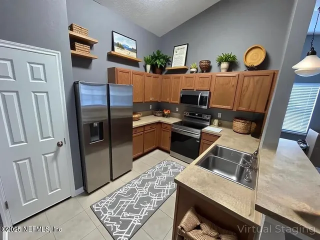 a kitchen with stainless steel appliances granite countertop a refrigerator a stove and a sink with wooden floors