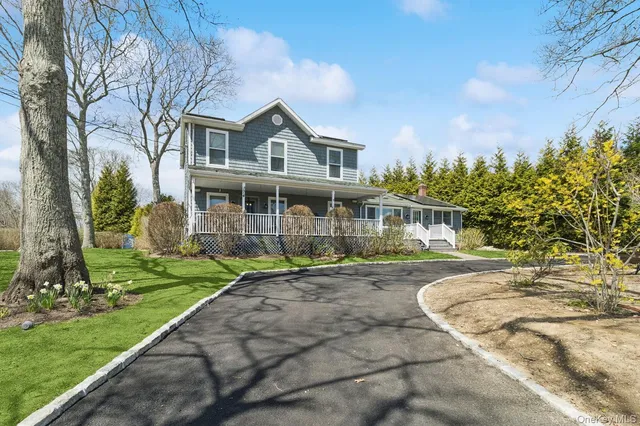 a front view of a house with a garden and trees