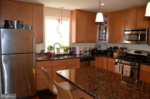a kitchen with stainless steel appliances granite countertop a sink stove and refrigerator