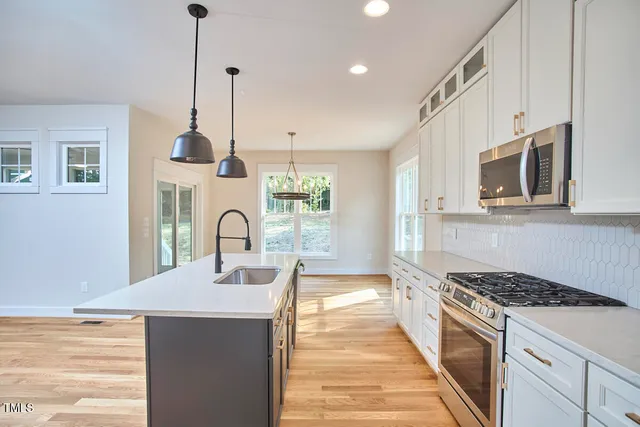 a kitchen with stainless steel appliances a stove a sink a microwave a counter space and cabinets