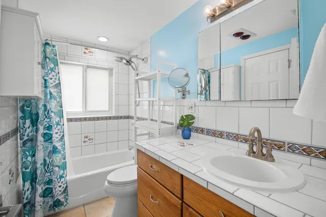 a bathroom with a granite countertop sink mirror vanity bathtub and a toilet