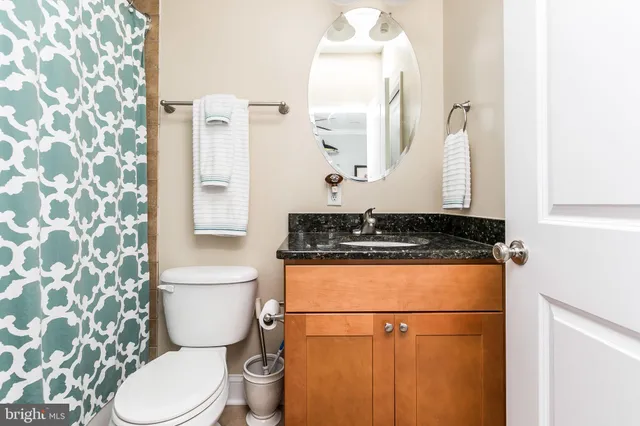a bathroom with a granite countertop toilet sink and mirror