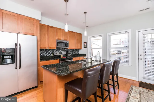 a kitchen with stainless steel appliances granite countertop a stove a refrigerator a kitchen island a table and chairs