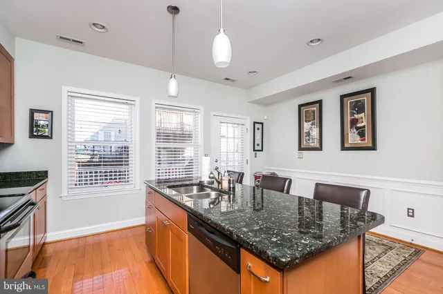 a room with granite countertop a sink and dishwasher with wooden floor