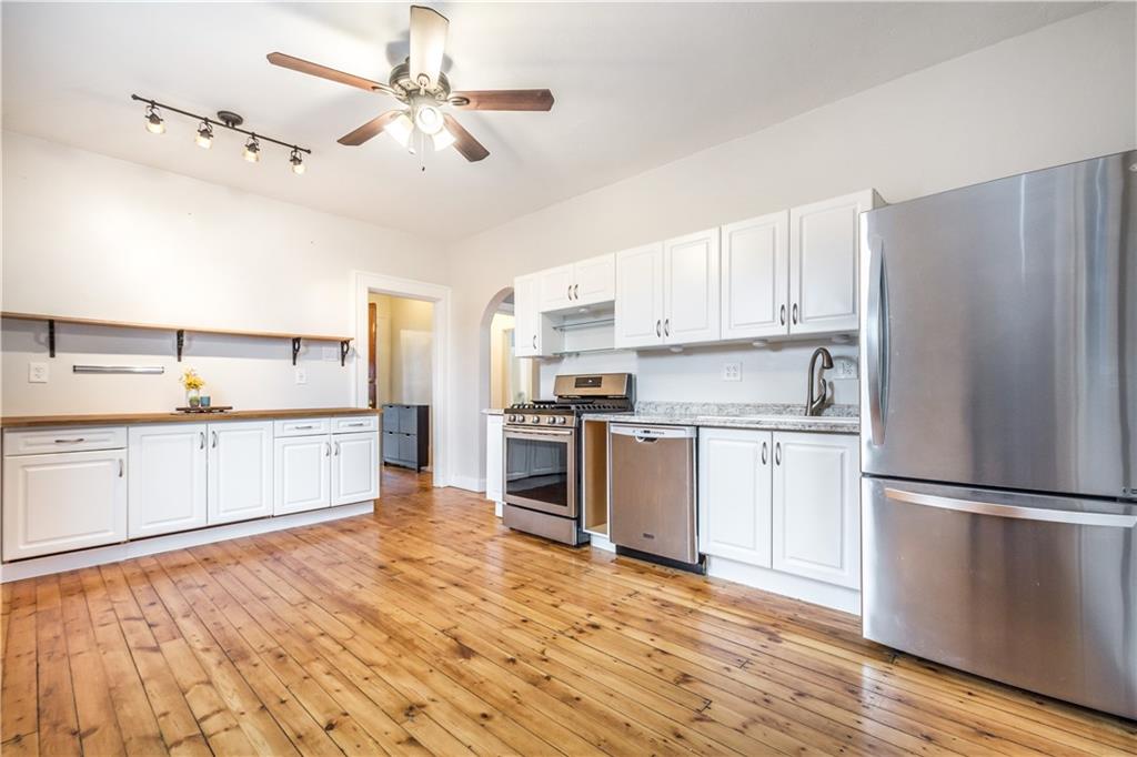 1549 McFarland Road Pittsburgh, PA 15216 - Photo 4 of 25 a kitchen with granite countertop a refrigerator oven a sink dishwasher and white cabinets with wooden floor
