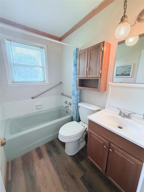 160 Bob White Road Denison, TX 75020 - Photo 23 of 29 Bathroom featuring a bathtub with a grab bar, wood-finish flooring, a wood vanity with integrated sink, a wall-mounted wooden cabinet, and a window with blinds