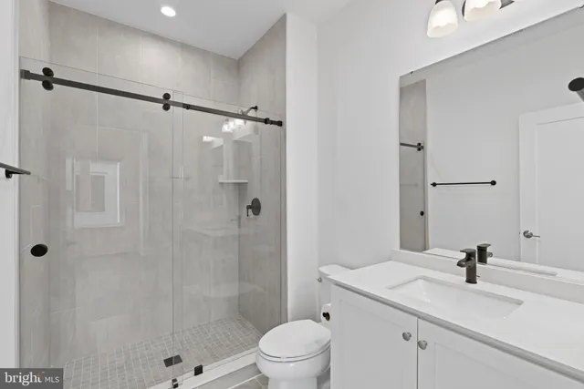 a bathroom with a granite countertop sink toilet a shower and a mirror