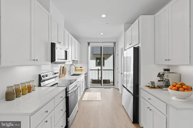a kitchen with stainless steel appliances a refrigerator sink and white cabinets