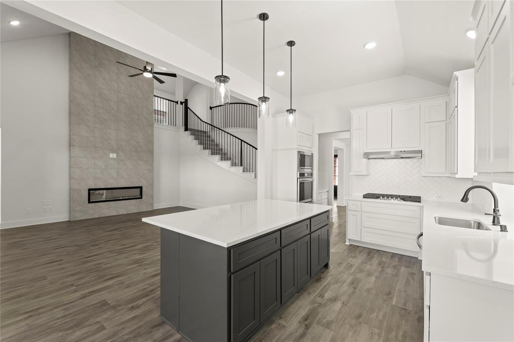 1314 Comal Drive Forney, TX 75126 - Photo 9 of 30 a large kitchen with kitchen island a stove a sink dishwasher a refrigerator and white cabinets with wooden floor