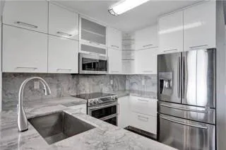 a kitchen with stainless steel appliances granite countertop a refrigerator a stove a sink and white cabinets