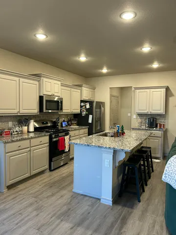 a kitchen with stainless steel appliances granite countertop wooden cabinets a sink dishwasher a stove and a refrigerator