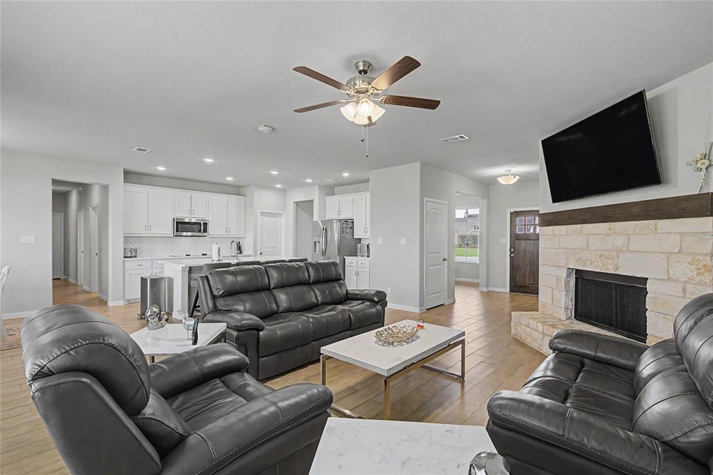 185 Chester Road Springtown, TX 76082 - Photo 2 of 40 Open-concept living space featuring wood-finish flooring, a stone fireplace with a wood mantle, and a ceiling fan