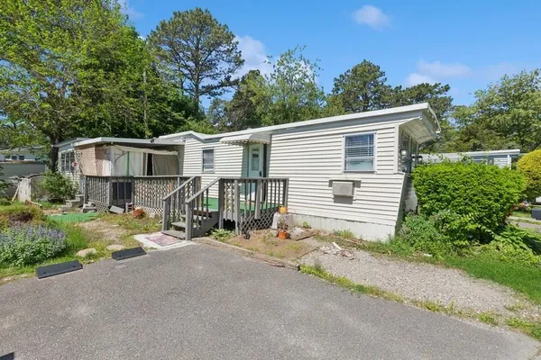 a view of a house with a small yard and large trees