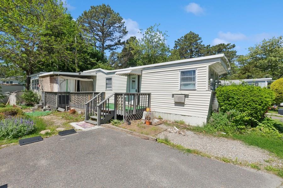 a view of a house with a small yard and large trees