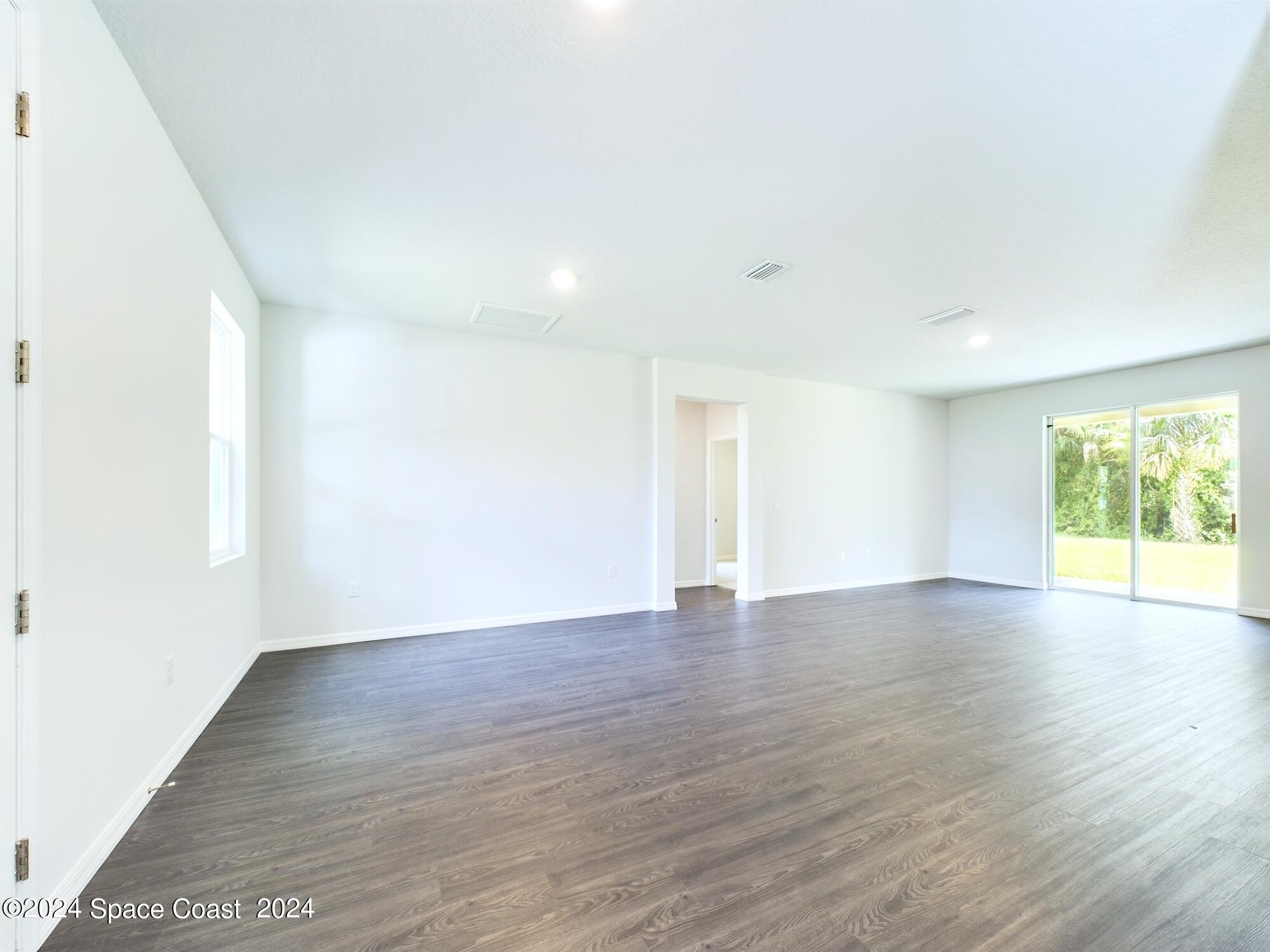 842 Angelico Road Northwest Palm Bay, FL 32907 - Photo 8 of 22 a view of an empty room with wooden floor and a window