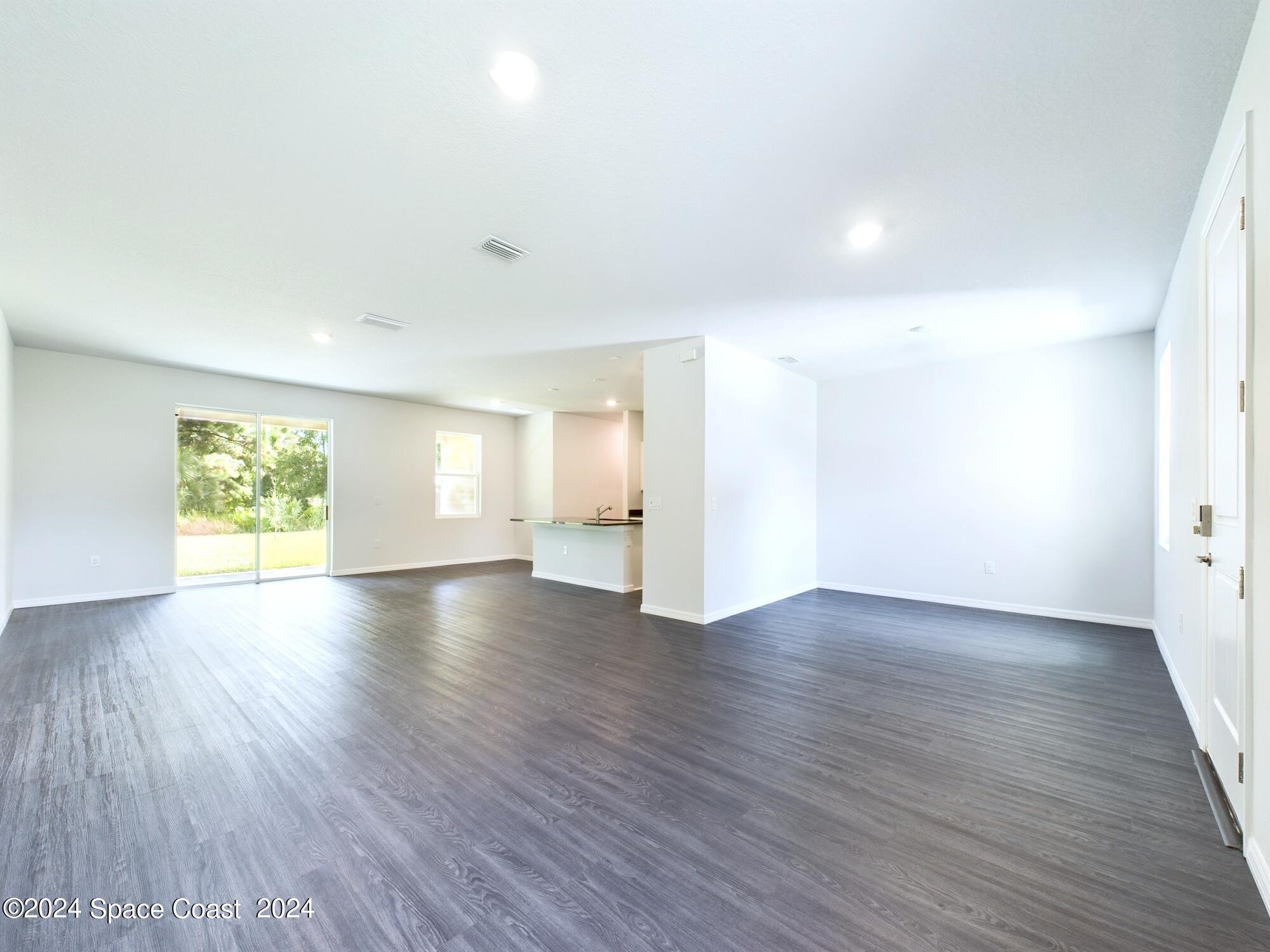 842 Angelico Road Northwest Palm Bay, FL 32907 - Photo 9 of 22 a view of an empty room with wooden floor and a window