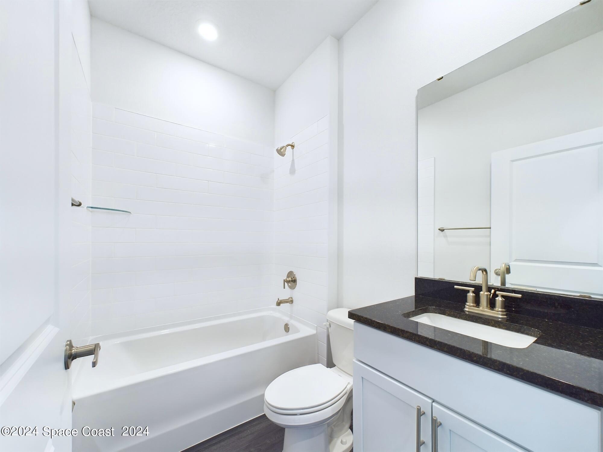 842 Angelico Road Northwest Palm Bay, FL 32907 - Photo 10 of 22 a bathroom with a granite countertop sink a toilet and a bathtub