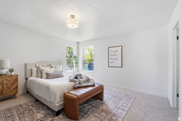 2460 Allison Way Syracuse, UT 84075 - Photo 13 of 24 Bright bedroom featuring multiple windows, neutral wall paint, textured carpeting, a flush mount ceiling light fixture, and white trim