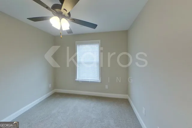 an empty room with a chandelier fan and windows