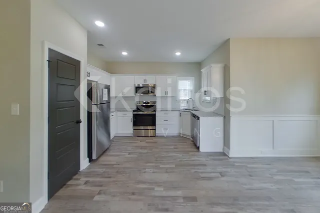 a kitchen with stainless steel appliances kitchen island granite countertop a refrigerator and a sink