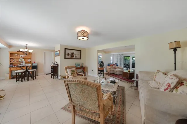 a view of a dining room and livingroom with furniture wooden floor a rug a painting and a chandelier
