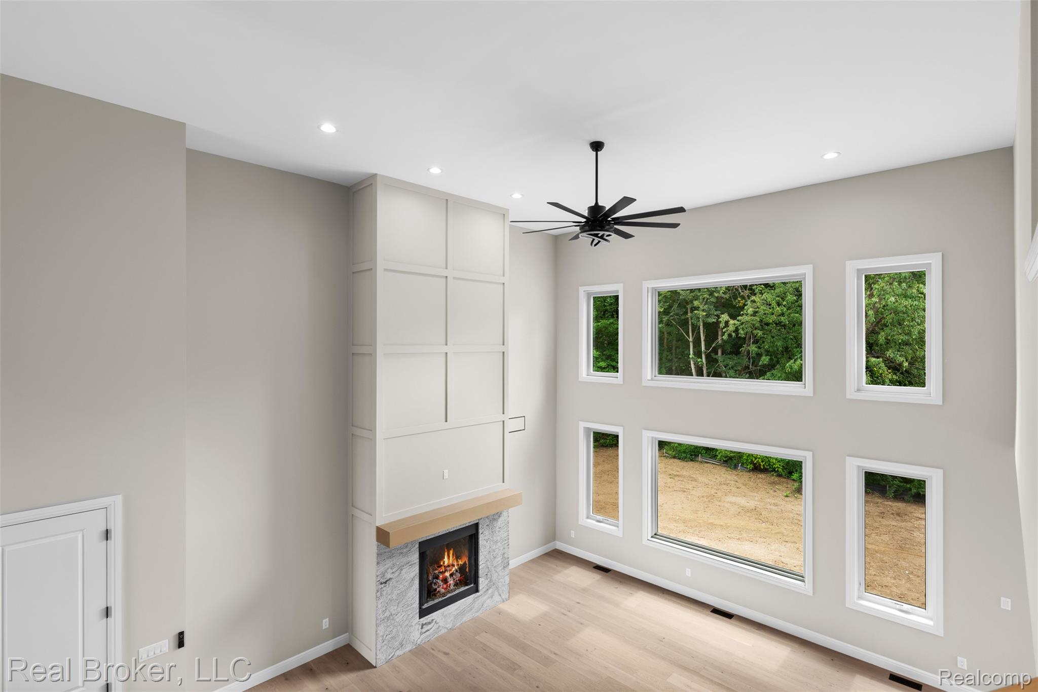 12114 22 Mile Road Utica, MI 48315 - Photo 54 of 70 Wood-finish flooring with a modern fireplace featuring a natural wood mantel and stone surround
