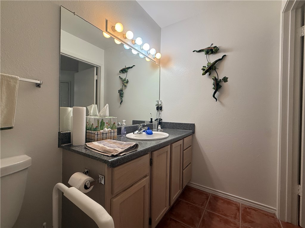 113 Santa Fe Rockport, TX 78382 - Photo 22 of 25 a bathroom with a granite countertop sink a toilet and a mirror