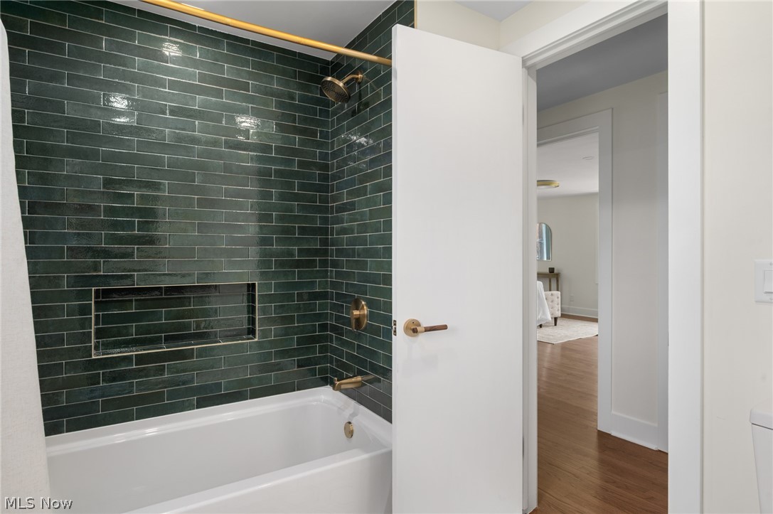 22625 Rye Road Shaker Heights, OH 44122 - Photo 26 of 38 Bathtub with dark green subway tile surround, integrated shower niche, and brushed brass fixtures