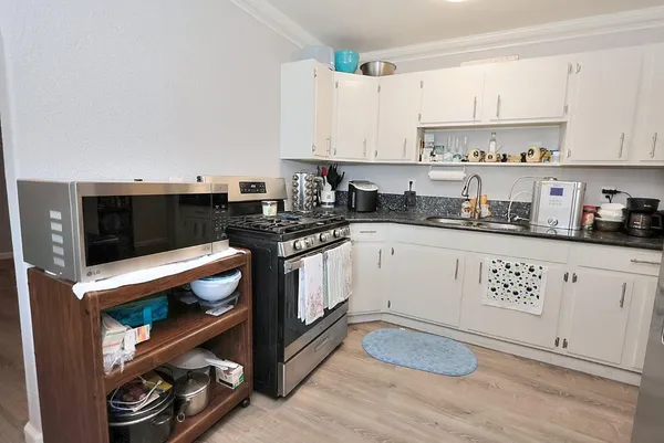 a kitchen with granite countertop a stove a sink and cabinets