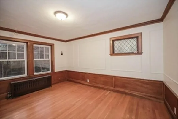 a view of an empty room with a window and wooden floor