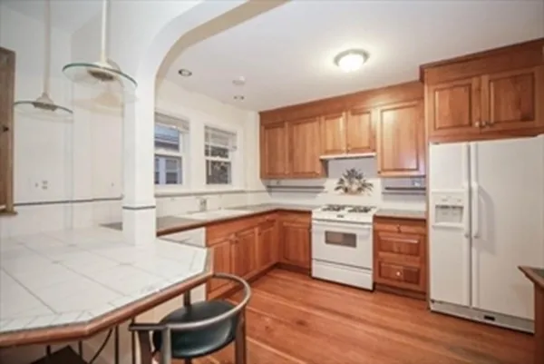 a kitchen with stainless steel appliances granite countertop a stove a sink dishwasher and a refrigerator with wooden floor