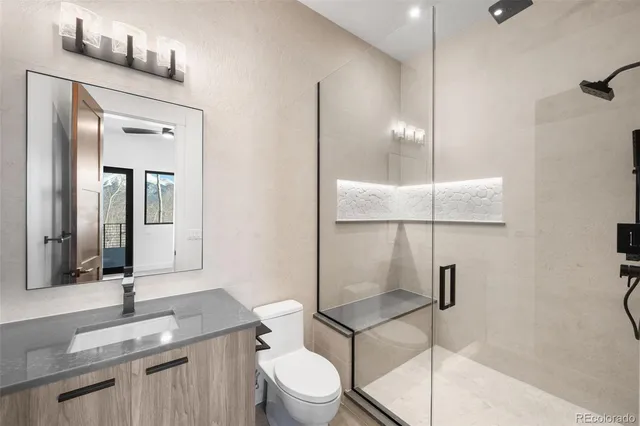 a bathroom with a granite countertop sink mirror vanity and toilet