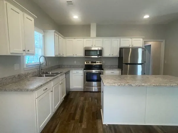 a kitchen with granite countertop a refrigerator and a stove top oven