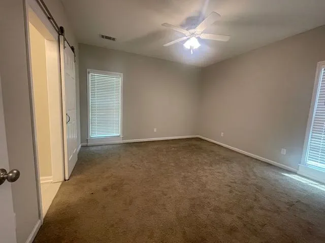 an empty room with a ceiling fan and window