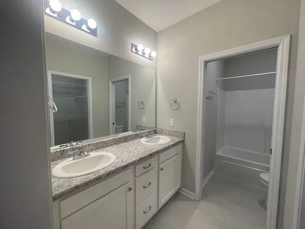 a bathroom with a granite countertop sink double vanity and a mirror