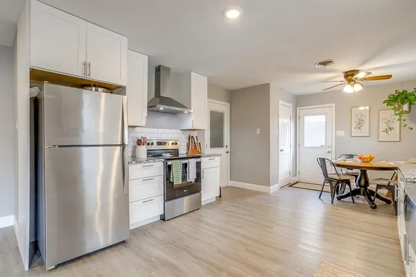 a kitchen with stainless steel appliances granite countertop a refrigerator a stove a sink dishwasher and a refrigerator with wooden floor