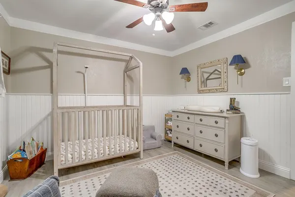 a bedroom with a baby bed a couch and dresser