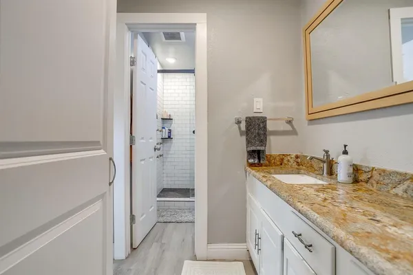 a bathroom with a granite countertop sink a mirror and shower