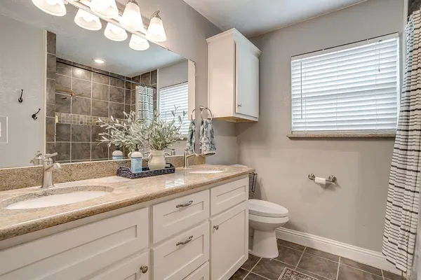 a bathroom with a granite countertop sink a toilet and a mirror