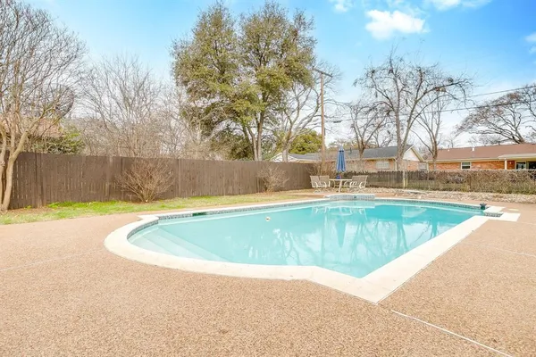 a view of a swimming pool with a yard and large trees