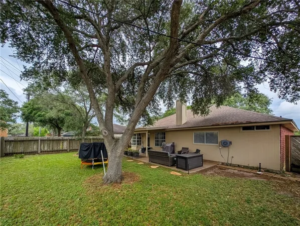 a view of a house with backyard and a tree