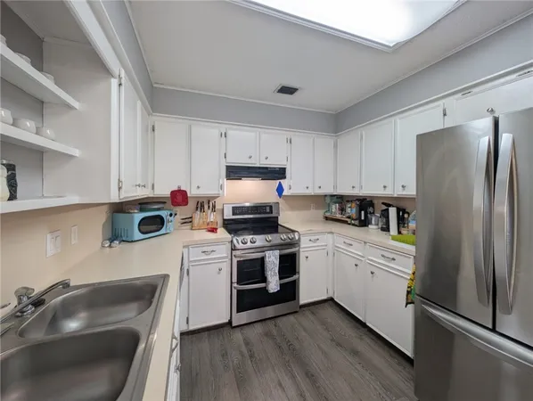 a kitchen with a sink white cabinets and stainless steel appliances