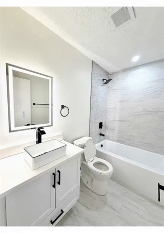 a bathroom with a bathtub shower sink mirror and toilet